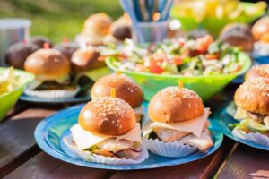 Buffet table with many mini burgers at outdoors birthday party for children, kids. Catering at weddi